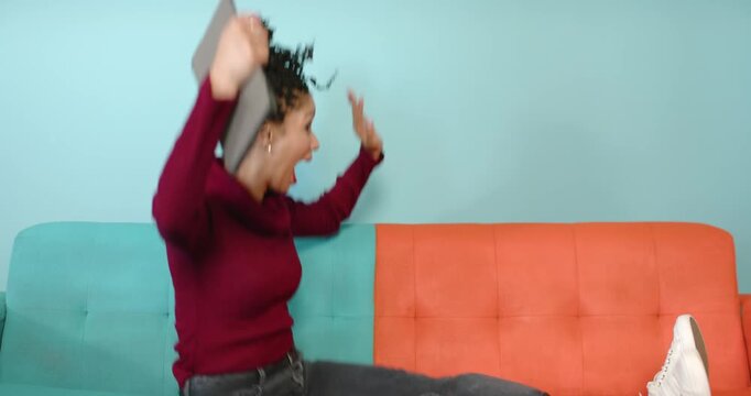 African American woman holding tablet in studio running toward two-tone sofa greeting, copy space - Powered by Adobe