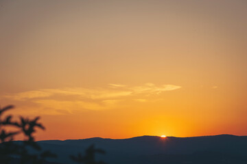 Captivating sunset paints the sky above distant mountains in warm hues during a serene evening