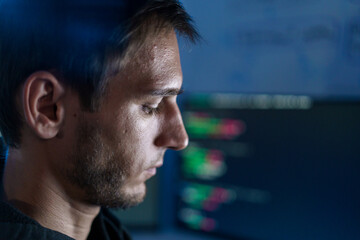 Fototapeta premium Caucasian male programmer coding late night in dark room.