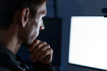 Caucasian male programmer coding late night in dark room.