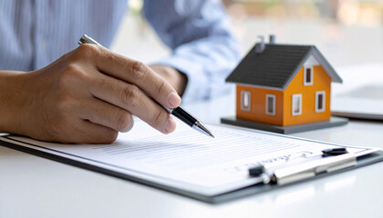 Signing real estate contract on clipboard with house model
