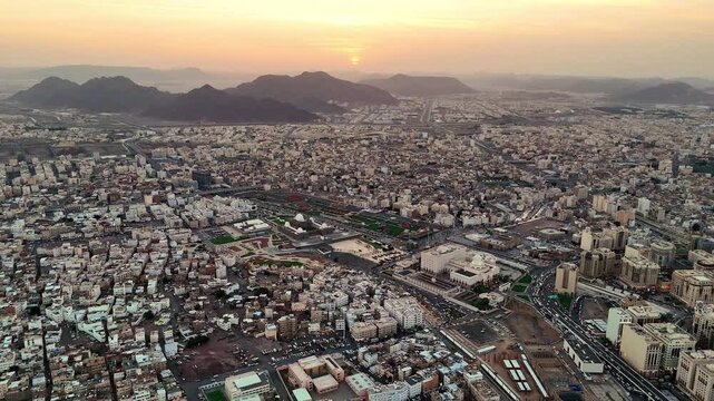 drone footage of Medina, Saudi Arabia, filmed at sunset. The video captures the vast urban landscape with residential buildings, and surrounding mountains bathed in golden hour light