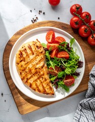 Top-down photo of grilled chicken breast with char marks, fresh greens, cherry tomatoes on white plate over wood board. Bright, clean, natural daylight, healthy meal.