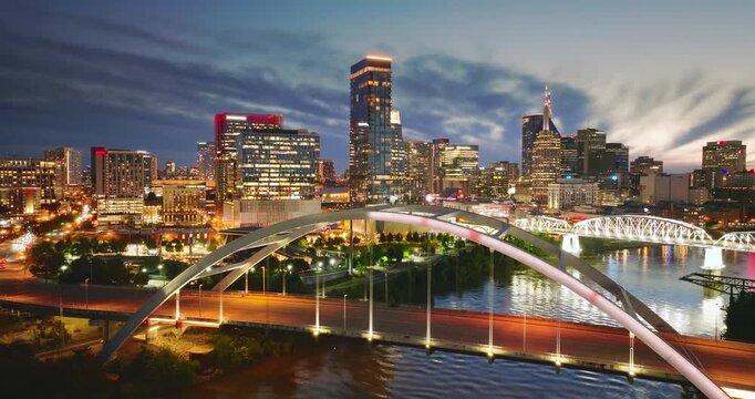 Nashville, Tennessee at night. Highway traffic on Korean Veterans Memorial Bridge with illuminated high skyscraper buildings in downtown district. American city with business financial district.