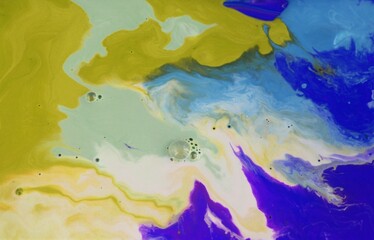 abstract background of blue and yellow mixed paints in water close up