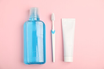 Mouthwash, toothbrush and toothpaste on pink background, flat lay