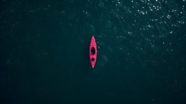 A vibrant pink kayak navigates the deep blue water, viewed from a breathtaking aerial perspective, embodying serene solitude and the thrill of personal exploration