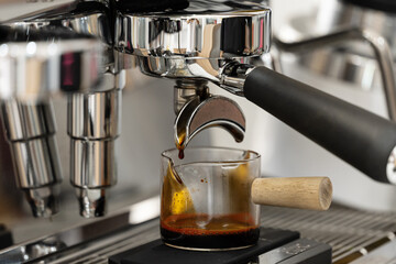 Coffee machine brewing espresso in to glass cup.Barista while preparing and working with coffee machine and making espresso coffee from arabica coffee beans.