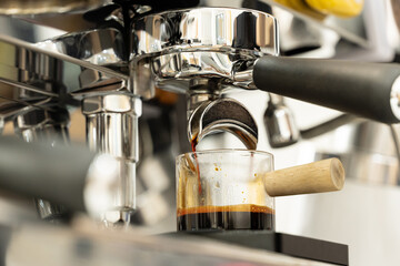 Coffee machine brewing espresso in to glass cup.Barista while preparing and working with coffee machine and making espresso coffee from arabica coffee beans.