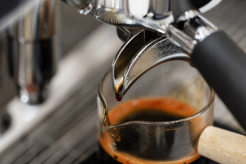 Coffee machine brewing espresso in to glass cup.Barista while preparing and working with coffee machine and making espresso coffee from arabica coffee beans.