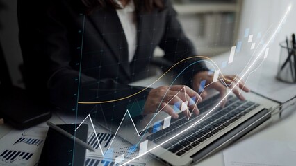 A business professional types on a laptop in a modern office setting, with financial graphs and charts superimposed, illustrating data analysis and trends. Copula