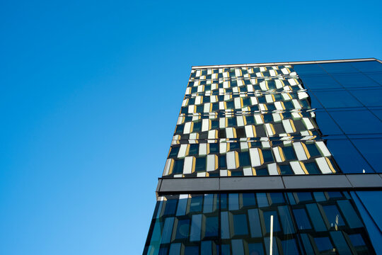 Modern office building façade in Stockholm with geometric glass patterns under clear blue sky, Scandinavian architecture showing perspective, rhythm and clarity for design projects