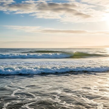 Gentle ocean waves rolling onto a sandy beach at sunset