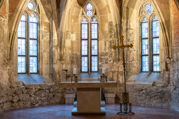 Medieval stone chapel interior with altar and cross
