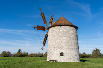 Rustic stone windmill in a grassy field