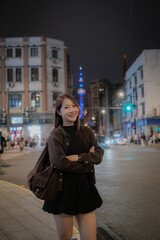 Fototapeta premium A woman is standing on a city street, wearing a black jacket and black skirt. traveller tourist concept.