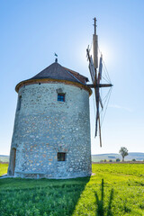 Rustic stone windmill in a grassy field