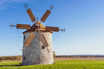 Rustic stone windmill in a grassy field