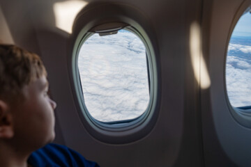 a boy looking out the window of an airplane during the flight