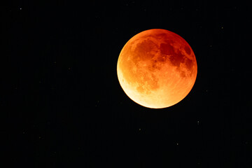 Blood moon during lunar eclipse with stars visible in night sky, dramatic astronomical phenomenon captured in vivid detail.