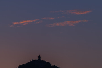 Sunset on hill with castle in silhouette on horizon