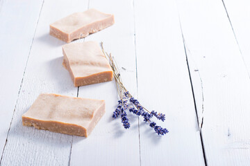handmade soaps and dried lavender flowers on white wood table background