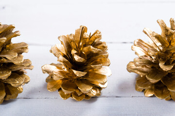 golden pine cones Christmas decoration on white wood table background