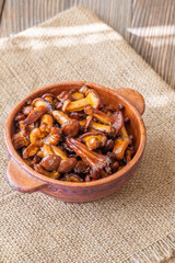 Rustic bowl filled with golden fried chanterelle mushrooms on table