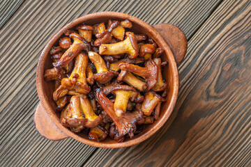 Rustic bowl filled with golden fried chanterelle mushrooms on table