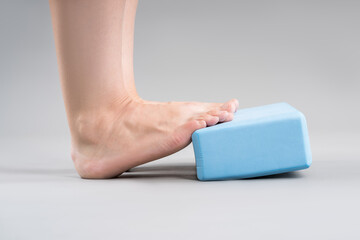 Individual balance training on a blue block with bare feet, demonstrating foot position and...