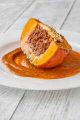 Portion of baked Hokkaido pumpkin with beef, tomato sauce, mozzarella cheese