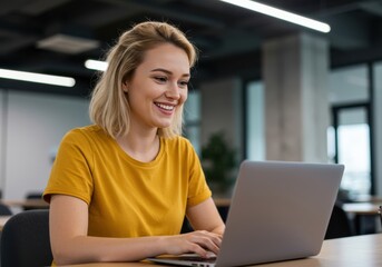 A young woman with blonde hair smiles while working on her laptop in a modern office environment