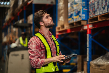 Warehouse workers and manager in reflective vests inspecting inventory, using digital tablet for stock control, logistics, supply chain management, and modern industrial warehouse operations.