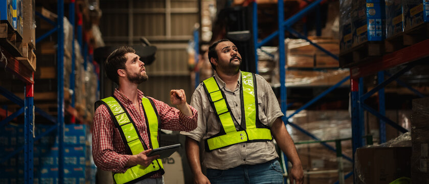 Warehouse worker working and checking the stock in the warehouse. Factory manager using digital tablet check barcode in industry factory logistic.
