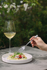 Hand holding fork eating fresh gourmet appetizer outdoors