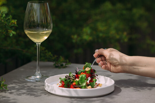 Woman enjoying fresh salad and white wine outdoors