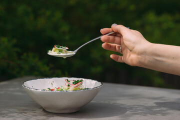 Hand holding spoon with cold soup with vegetables
