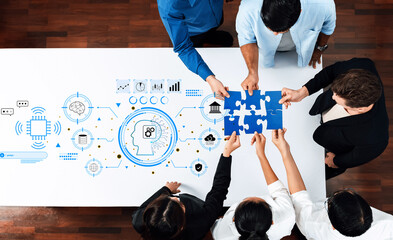 Diverse team collaborates around a table, engaging in problem-solving with puzzle pieces while technology concepts visually illustrate brainstorming efforts. Trope