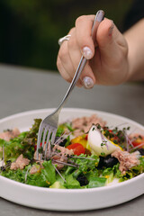 Woman eating fresh healthy tuna salad with fork