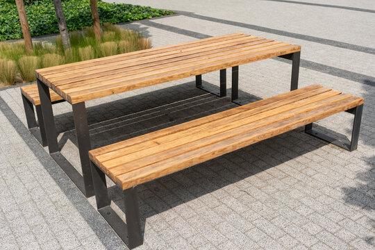 Wooden table with benches in modern urban square. Concept of social interaction, community connection, and functional public design in everyday city environment.