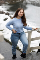 A girl in a park in winter near white railings