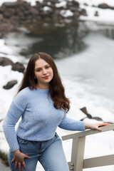A girl in a park in winter near white railings