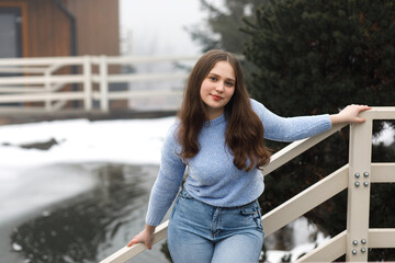 A girl in a park in winter near white railings