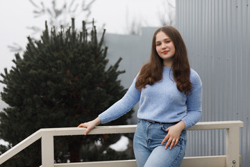 A girl in a park in winter near white railings