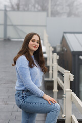 A girl in a park in winter near white railings