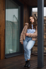 A girl on the terrace in blue jeans and a warm jacket