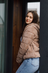 A girl on the terrace in blue jeans and a warm jacket
