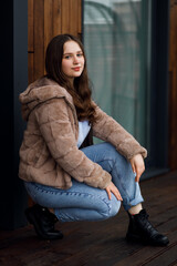 A girl in blue jeans and a warm jacket on the terrace
