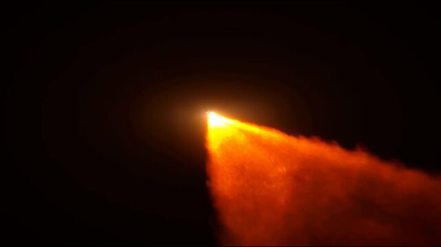 A rocket speeds forward in space, releasing bright flames and leaving a trail of fire and smoke behind