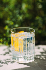 Refreshing drink with lemon and ice on sunny day